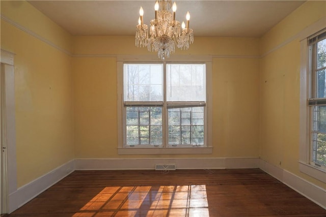 empty room featuring dark wood-style floors, baseboards, visible vents, and an inviting chandelier