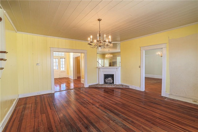 unfurnished living room featuring ornamental molding, a brick fireplace, dark wood finished floors, and a notable chandelier