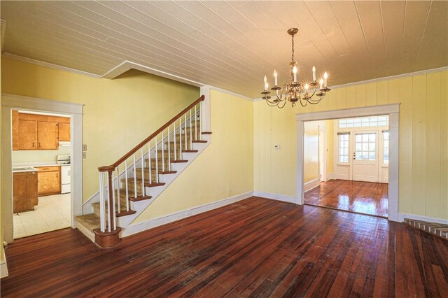 interior space featuring a notable chandelier, wood finished floors, baseboards, stairs, and ornamental molding