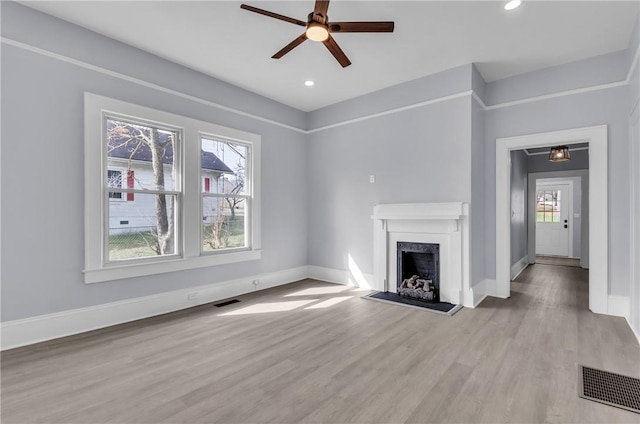 unfurnished living room with a wealth of natural light, visible vents, and wood finished floors