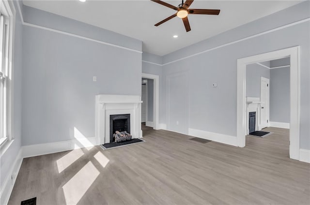 unfurnished living room featuring a fireplace, visible vents, ceiling fan, wood finished floors, and baseboards