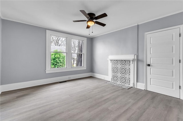 spare room with visible vents, ornamental molding, a ceiling fan, wood finished floors, and baseboards