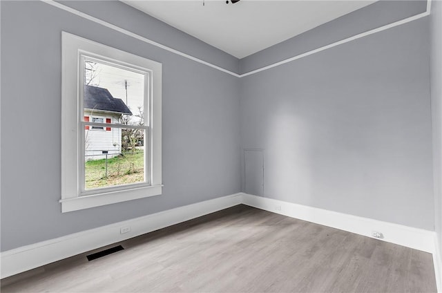 unfurnished room featuring visible vents, baseboards, and wood finished floors