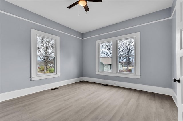 spare room featuring visible vents, baseboards, and wood finished floors