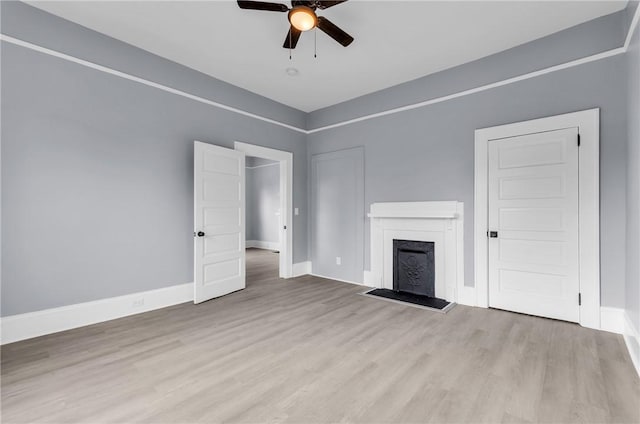 unfurnished living room featuring a ceiling fan, a fireplace, baseboards, and wood finished floors