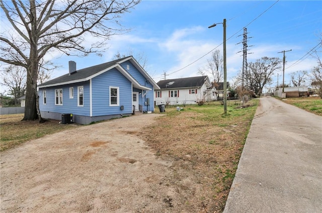 exterior space with driveway, a chimney, and fence