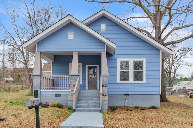 bungalow-style home with a porch, a front yard, crawl space, and fence