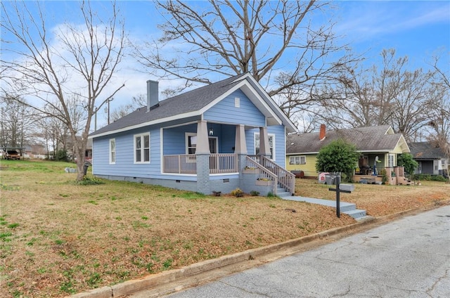 bungalow featuring covered porch, a front lawn, crawl space, and a chimney