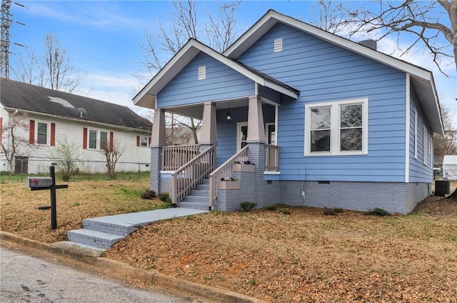 bungalow-style house with a porch, central AC unit, crawl space, fence, and a front lawn