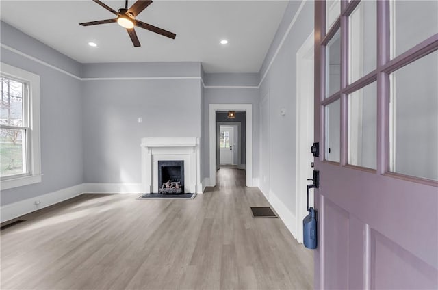 unfurnished living room featuring light wood-style flooring, a fireplace, visible vents, and baseboards