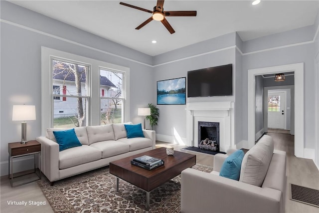 living room with plenty of natural light, a fireplace, baseboards, and wood finished floors