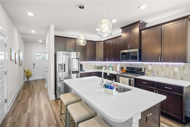 kitchen featuring a kitchen breakfast bar, light wood-type flooring, stainless steel appliances, and a kitchen island with sink