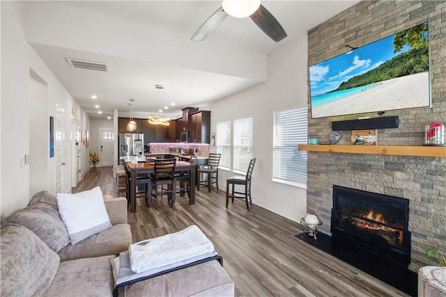 living room with a fireplace, ceiling fan, and dark wood-type flooring