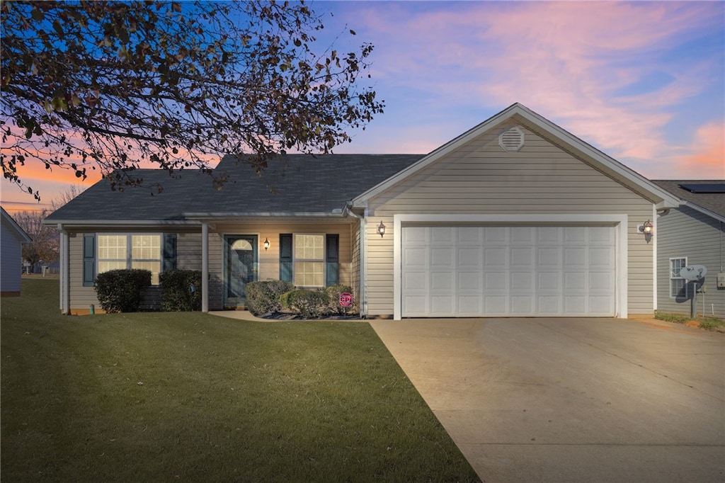 ranch-style home with a garage and a lawn