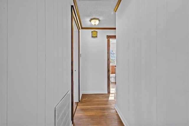 hallway featuring wood walls, hardwood / wood-style floors, and a textured ceiling