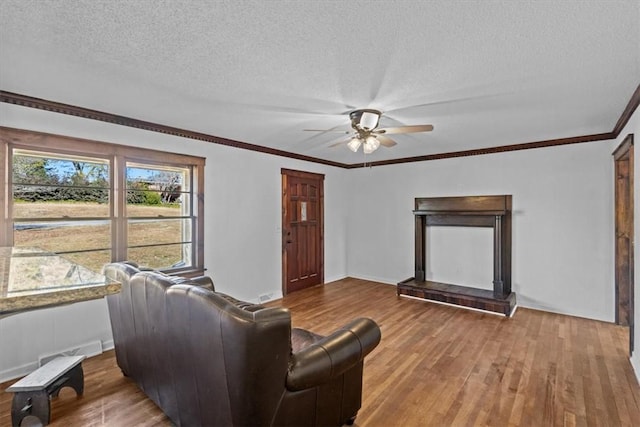 living room featuring ceiling fan, crown molding, wood-type flooring, and a textured ceiling