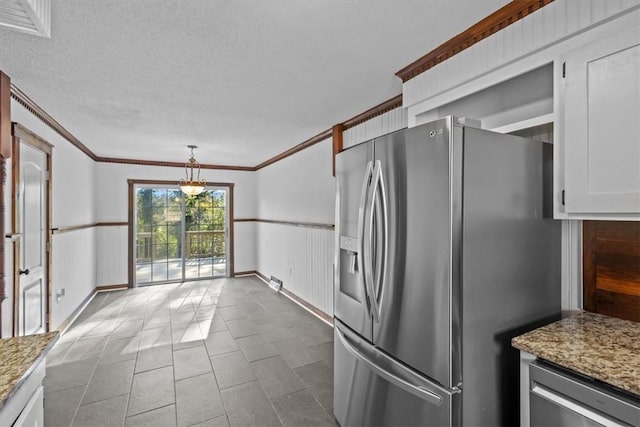 kitchen featuring light stone counters, stainless steel appliances, crown molding, decorative light fixtures, and white cabinetry