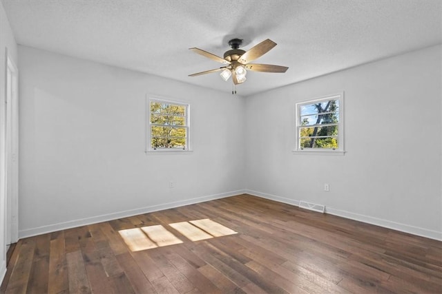 spare room featuring ceiling fan, dark wood-type flooring, and a textured ceiling