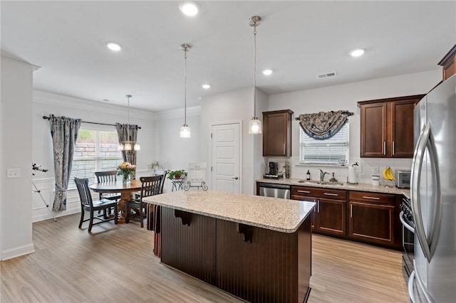 kitchen featuring a center island, a kitchen breakfast bar, hanging light fixtures, light hardwood / wood-style floors, and stainless steel appliances