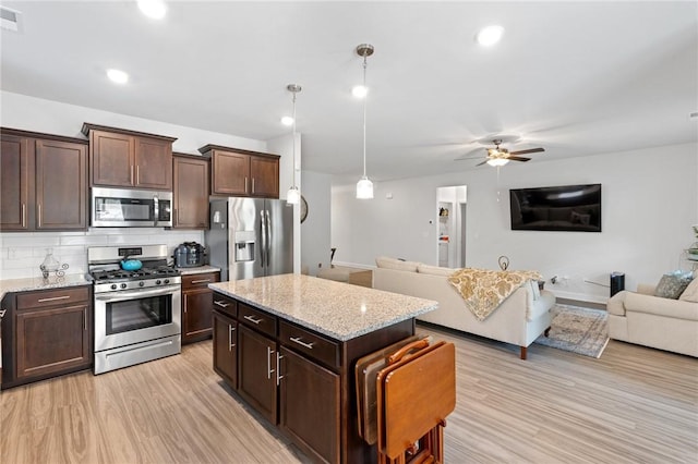 kitchen with hanging light fixtures, light hardwood / wood-style flooring, decorative backsplash, appliances with stainless steel finishes, and dark brown cabinetry