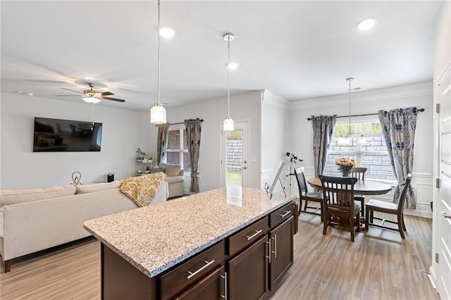 kitchen with dark brown cabinetry, ceiling fan, light hardwood / wood-style flooring, pendant lighting, and ornamental molding