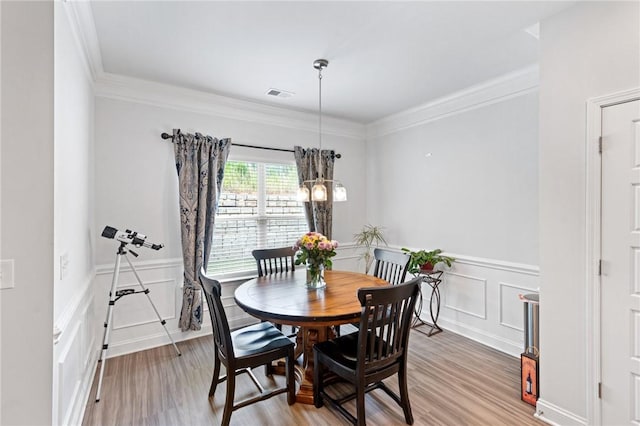 dining room with light hardwood / wood-style floors, an inviting chandelier, and crown molding