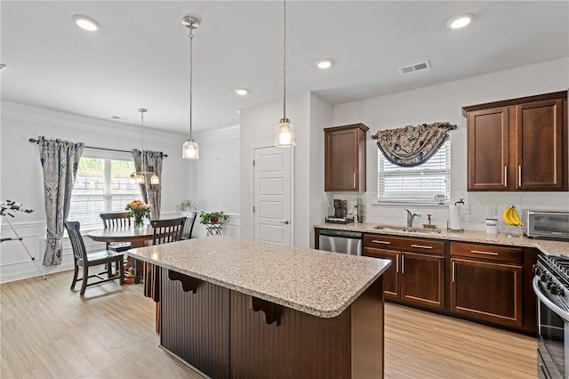 kitchen featuring sink, hanging light fixtures, appliances with stainless steel finishes, tasteful backsplash, and a kitchen bar