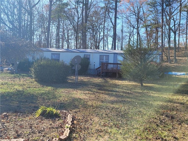 manufactured / mobile home with a front lawn, a deck, and a trampoline