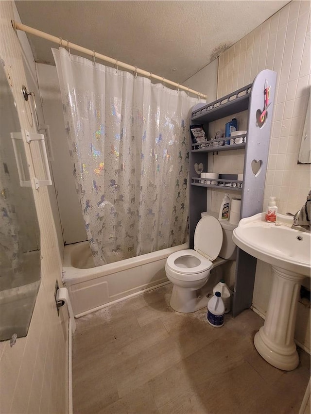 bathroom featuring shower / tub combo with curtain, a textured ceiling, and toilet