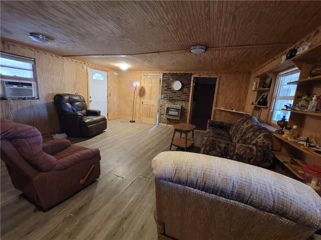 living room with wooden walls, wood-type flooring, a fireplace, and a wealth of natural light