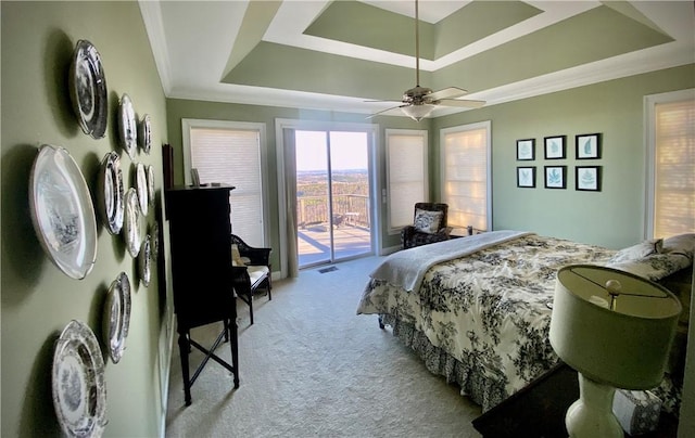 bedroom with a tray ceiling, access to exterior, ceiling fan, and light colored carpet