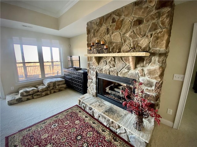 carpeted living room with a stone fireplace and ornamental molding