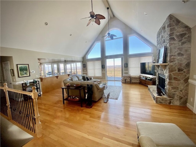 living room featuring beam ceiling, a fireplace, high vaulted ceiling, and light wood-type flooring