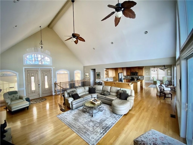 living room featuring beam ceiling, light hardwood / wood-style flooring, high vaulted ceiling, and ceiling fan