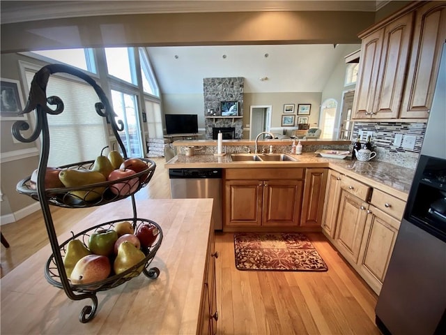 kitchen featuring sink, a stone fireplace, light hardwood / wood-style flooring, lofted ceiling with beams, and stainless steel dishwasher