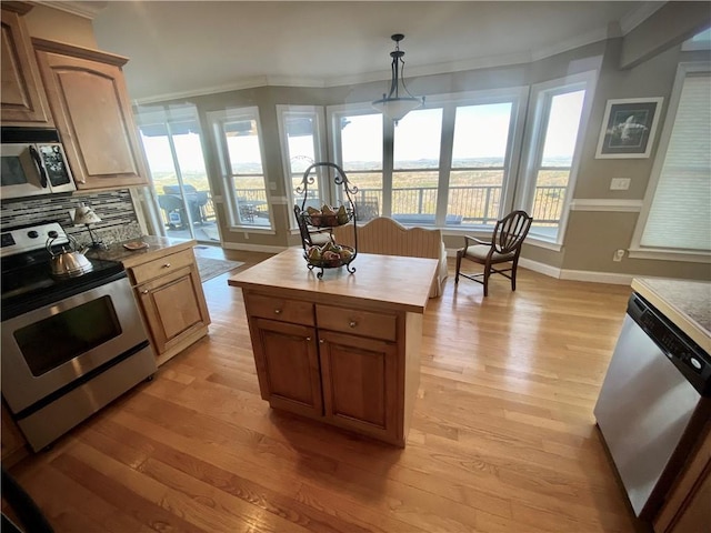 kitchen featuring tasteful backsplash, crown molding, pendant lighting, appliances with stainless steel finishes, and light wood-type flooring