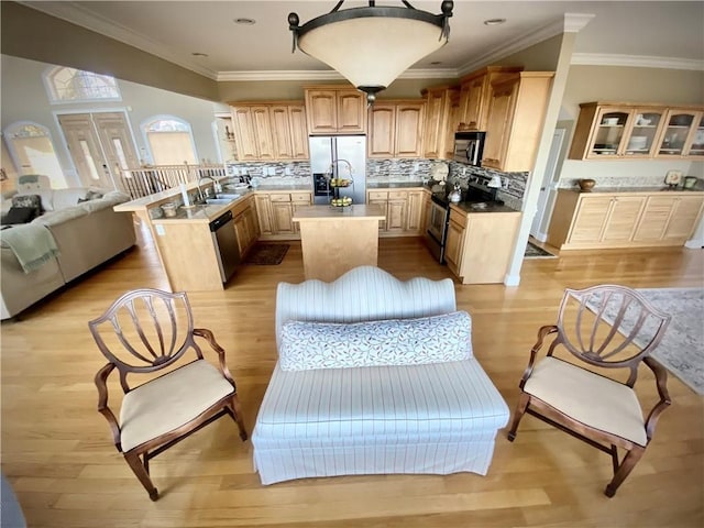 kitchen with sink, light brown cabinets, decorative backsplash, a kitchen island, and appliances with stainless steel finishes