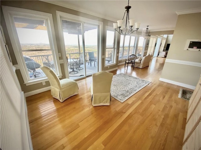 living room with crown molding, light hardwood / wood-style floors, and a notable chandelier