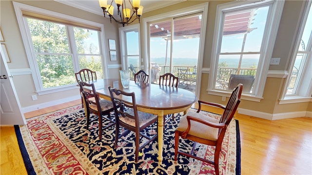 dining space with crown molding, plenty of natural light, a chandelier, and light hardwood / wood-style flooring