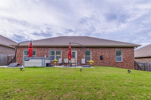 rear view of property with a patio area, a hot tub, and a yard