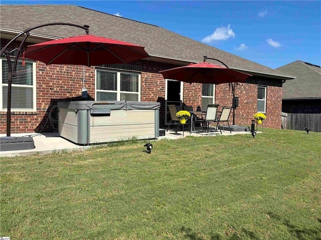 rear view of house with a lawn, a hot tub, and a patio area