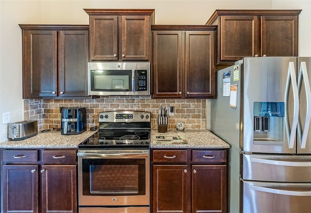 kitchen featuring backsplash, light stone counters, and appliances with stainless steel finishes