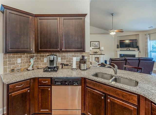 kitchen with sink, vaulted ceiling, light stone counters, ceiling fan, and stainless steel dishwasher