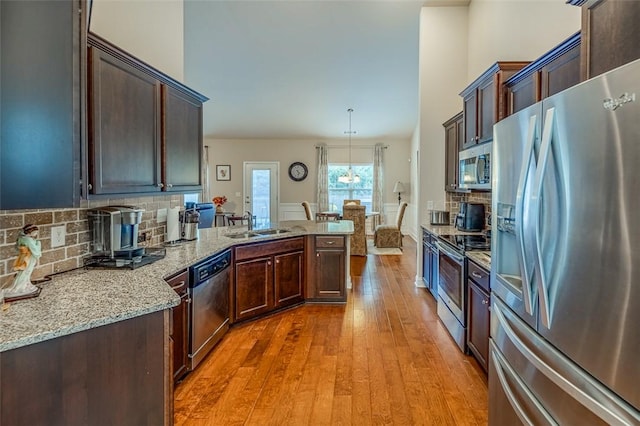 kitchen with sink, tasteful backsplash, hanging light fixtures, light stone countertops, and appliances with stainless steel finishes