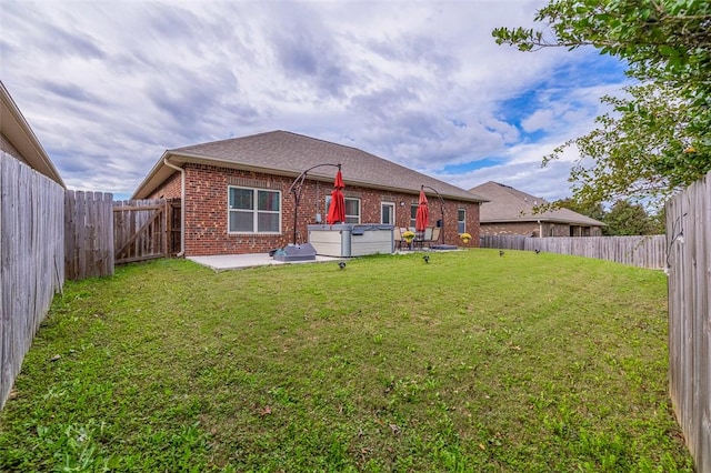 back of house with a patio, a yard, and a hot tub