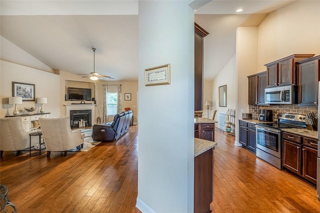 kitchen featuring light stone counters, light hardwood / wood-style floors, backsplash, dark brown cabinetry, and appliances with stainless steel finishes