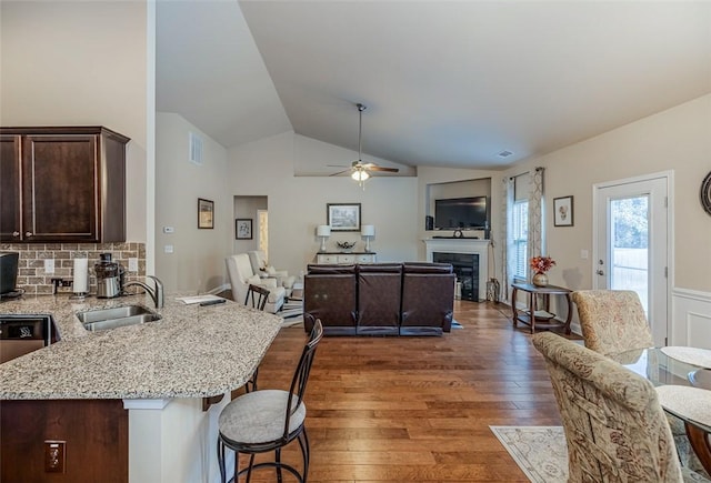 interior space with sink, a kitchen bar, ceiling fan, dark brown cabinets, and dark hardwood / wood-style floors