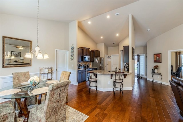 dining room featuring sink, ceiling fan with notable chandelier, high vaulted ceiling, and dark hardwood / wood-style floors