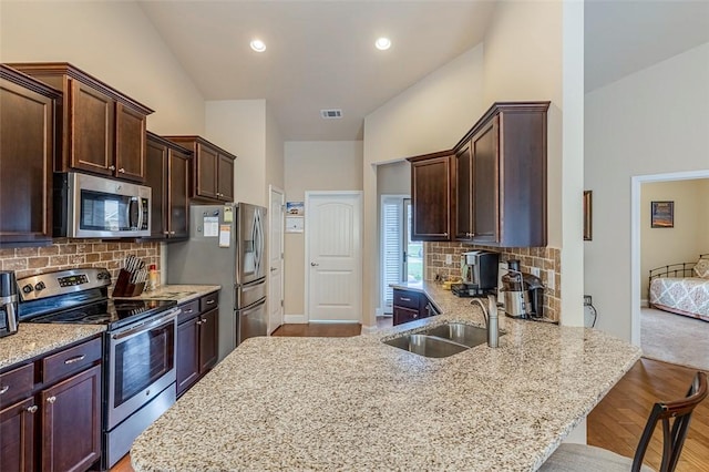 kitchen featuring kitchen peninsula, stainless steel appliances, backsplash, and a kitchen breakfast bar