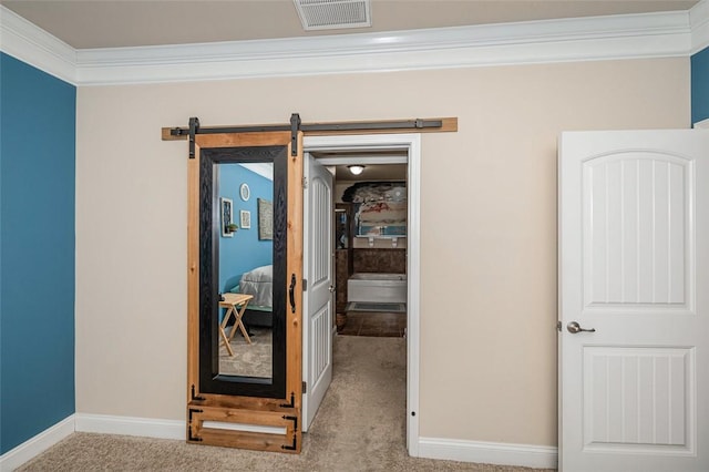 hall featuring a barn door, light colored carpet, and crown molding